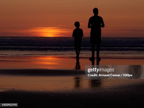 a father and son watching a sunset,lacanau,france - abstrait stock-fotos und bilder