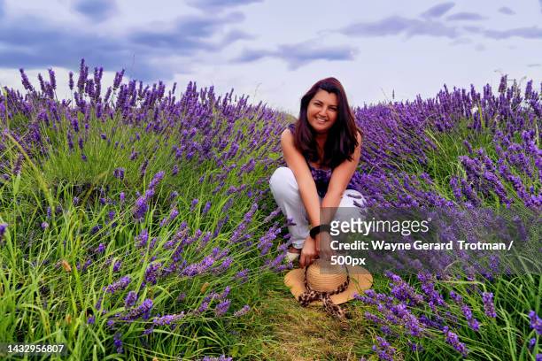portrait of smiling woman crouching on field,surrey,united kingdom,uk - wayne gerard trotman stockfoto's en -beelden