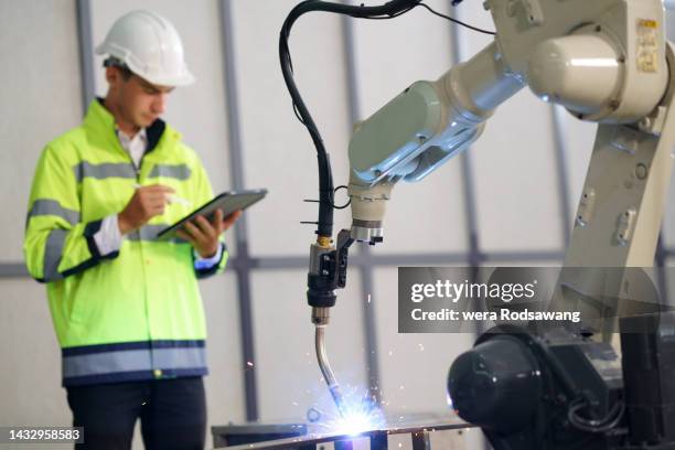 industrial engineer testing automatic robotic arm welding machine - bauingenieurwesen stock-fotos und bilder