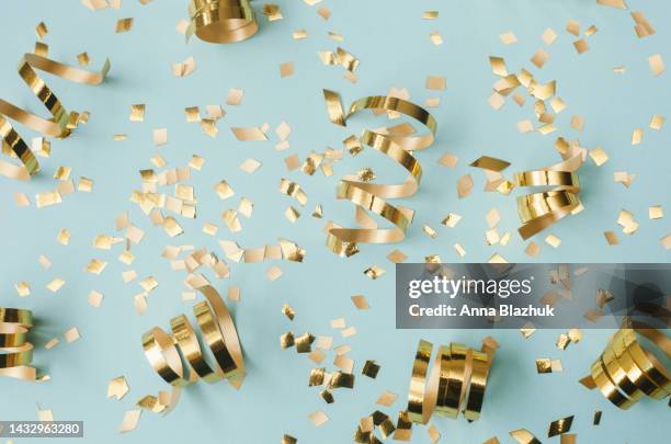 glittering golden confetti decoration over blue background for holidays, new year and christmas - nieuwjaar stockfoto's en -beelden