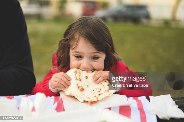 süßes kleines mädchen isst ihren snack. italienisches essen, piadina. - toddler eating sandwich stock-fotos und bilder