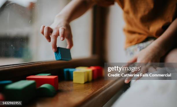 a child picks up a wooden building block - kinder muster fotografías e imágenes de stock