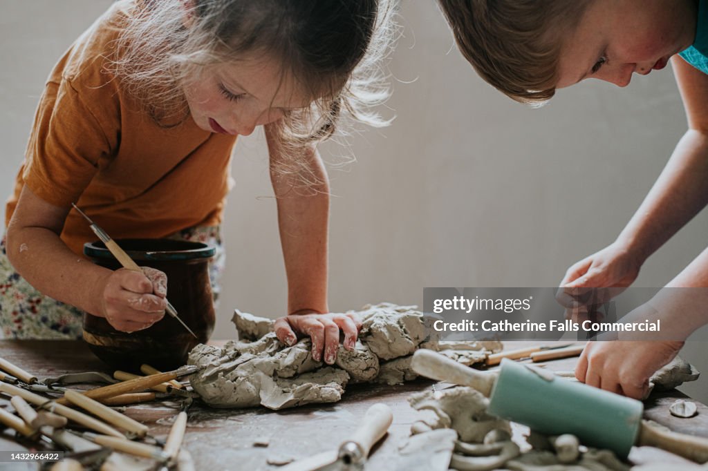 Two young children enjoy a creative activity using clay