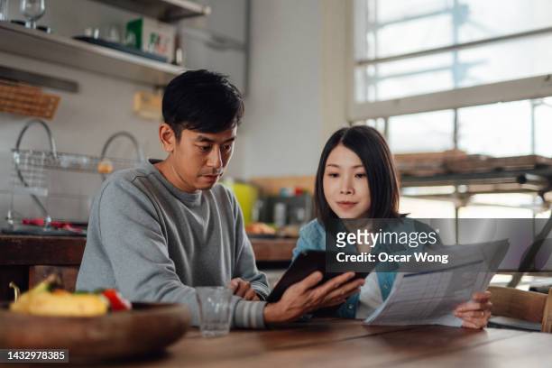 asian couple planning home finance with digital tablet at home - finanzplanung stock-fotos und bilder