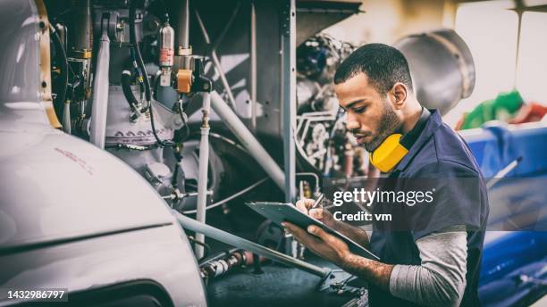 aviation mechanic looking at helicopter engine repair checklist - romp onderdeel van voertuig stockfoto's en -beelden