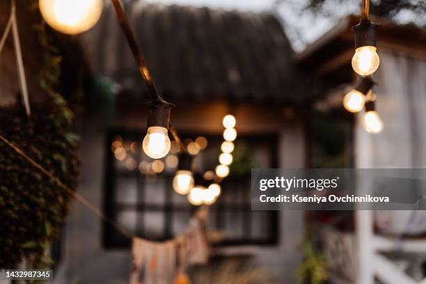 many light bulbs on the wire. lighting in the cafe. garland of lamps - terrasse bar stock-fotos und bilder