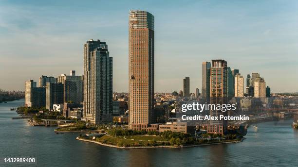 hunter’s point south phase 2 with luxury apartments on the shore of the east river with towers of long island city behind. - long island city stockfoto's en -beelden