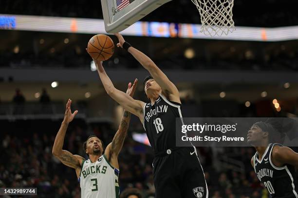 Yuta Watanabe of the Brooklyn Nets grabs a rebound in front of George Hill of the Milwaukee Bucks during the first half of a preseason game at Fiserv...