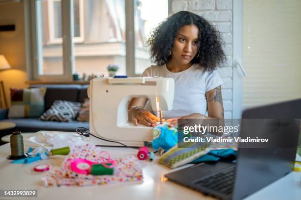 a young woman is learning sewing on machine at home - stop watch stockfoto's en -beelden