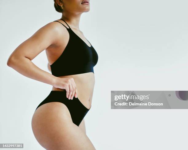 curvy woman in fashion black underwear against a mockup grey studio background. beauty model standing alone, isolated and showing her perfect body. take care of your body and health - curvy black women stockfoto's en -beelden