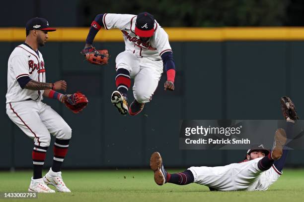 Dansby Swanson of the Atlanta Braves makes a catch for an out as Michael Harris II jumps over him and Eddie Rosario watches on a hit by J.T. Realmuto...