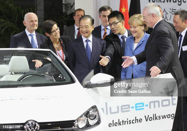 Chinese Premier Wen Jiabao gets a little encouragement to climb into a Volswagen EOS electric car by German Chancellor Angela Merkel and Volkswagen...