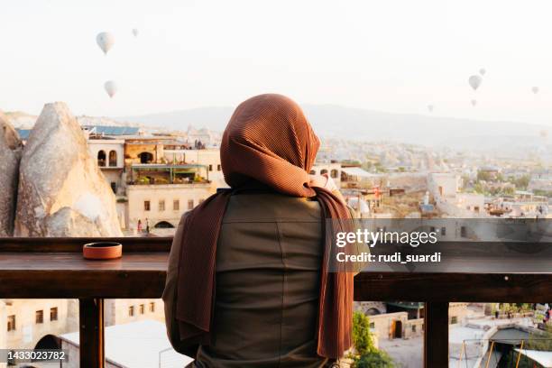 rear view of muslim woman sitting on rooftop cafe in cappadocia - huvudduk bildbanksfoton och bilder