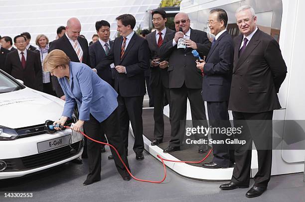 German Chancellor Angela Merkel plugs in a Volkswagen electric car as Chinese Premier Wen Jiabao , Volkswagen CEO Martin Winterkorn and Lower Saxony...