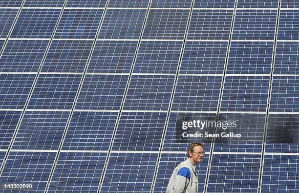 Volkswagen worker walks past an array of photovoltaic panels during a visit to the Volkswagen factory by Chinese Premier Wen Jiabao and German...