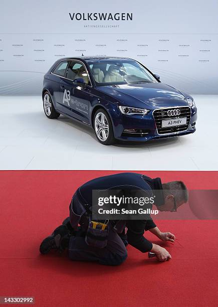 Worker makes last-minute improvements to the red carpet before the arrival of Chinese Premier Wen Jiabao next to an Audi A3 electric car at the...