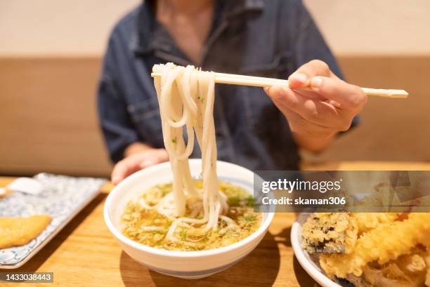 hand using chopstick picking hot soup udon noodle with tempura japanese style - udon noodles stock pictures, royalty-free photos & images