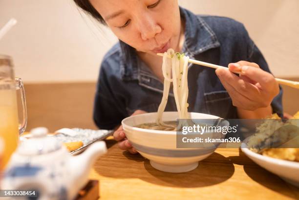 hand using chopstick picking hot soup udon noodle with tempura japanese style - udon noodles stock pictures, royalty-free photos & images