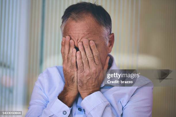 hombre de mediana edad con las manos cubriendo la cara - hombre llorando fotografías e imágenes de stock