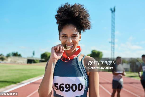 female athlete, runner and black woman bite medal after win for sprinting or olympic event at a stadium and track. happy female champion enjoying celebration for winning award at sports competition - sportsperson medal stock pictures, royalty-free photos & images