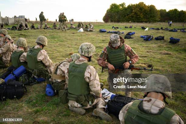 Ukrainian recruits sit in rows as they learn how to dissemble and maintain their weapons, during a field training session with the UK armed forces on...