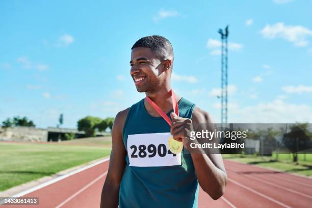 winner, medal and runner for sports race of a black man with smile for achievement in competitive fitness exercise. happy athletic african american male in running sport celebrating win at stadium - sportsperson medal stock pictures, royalty-free photos & images