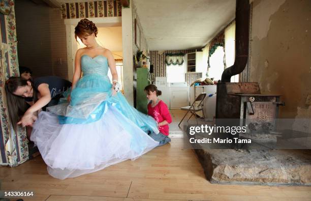 Brittany Brewer fixes her gown as she prepares for the Owsley County High School prom next to a wood stove in the home where she lives with her...