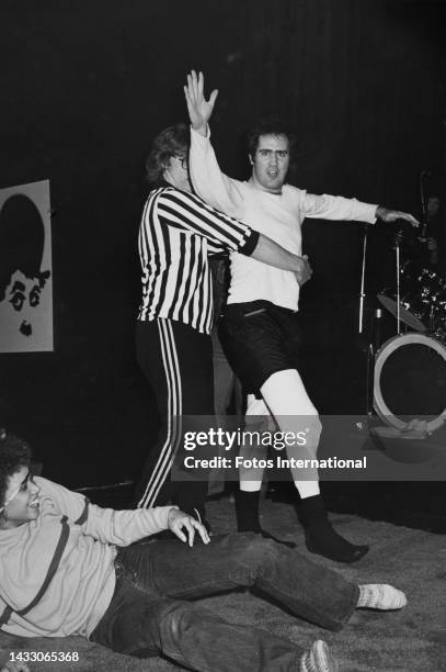 American comedian Andy Kaufman is held by the referee during a match against female wrestler Lena Home, Hollywood, California, December 1979.