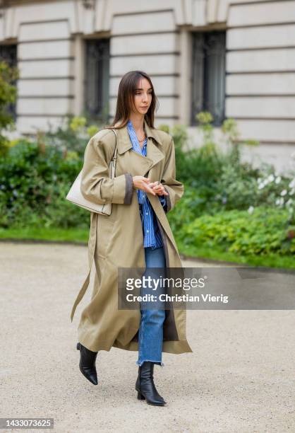 Guest wears trench coat, denim jeans outside Zimmermann during Paris Fashion Week - Womenswear Spring/Summer 2023 : Day Eight on October 03, 2022 in...