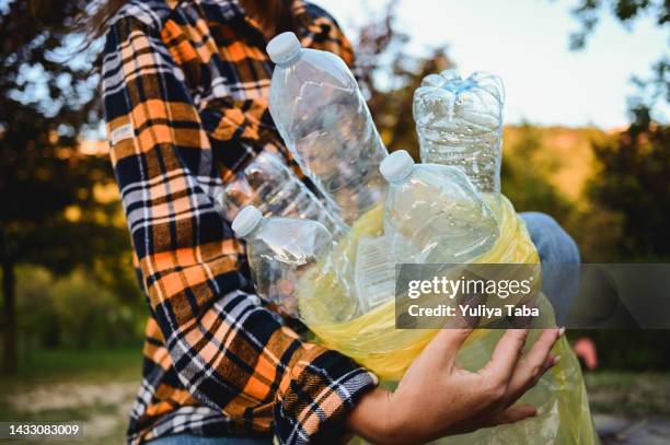 gros plan sur les mains d’une femme tenant un sac en plastique avec des déchets en plastique. bouteilles à ordures - sac poubelle photos et images de collection