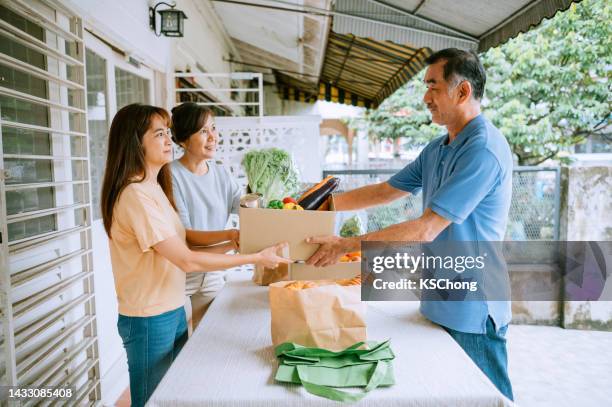 an asian chinese retired senior man donate some food to food bank center - distribution center stockfoto's en -beelden