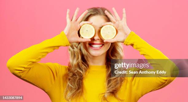 woman, hands with lemon on eyes and health diet on a studio background. wellness, food and healthy lifestyle of happy girl with fresh citrus fruits for vitamins, minerals and nutrition with a smile. - vitamins and minerals imagens e fotografias de stock