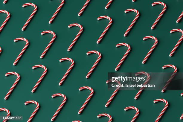 illustration 3d of a pattern of red and white candy canes placed in horizontal rows on a green background. - green christmas designs stock pictures, royalty-free photos & images