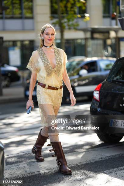 Guest wears silver and large crystal earrings, a brown shiny leather with large crystal pendant necklace, a pale yellow tulle / lace print pattern...