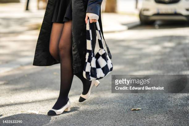 Guest wears a black long silk coat, a black pleated / accordion short skirt, a beige wool mittens, a black and white checkered print pattern fluffy...
