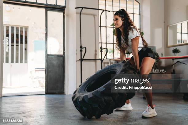 young woman exercising with a tire in a gym - hiit stock pictures, royalty-free photos & images