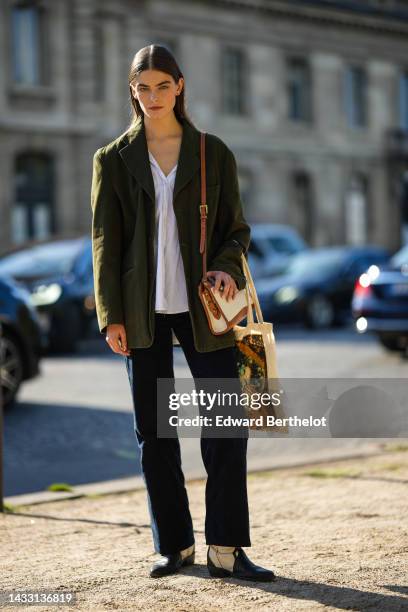 Guest wears a white shirt, a khaki blazer jacket, black denim wide legs pants, a beige fabric and camel shiny leather shoulder bag, black leather and...