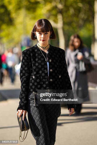 Guest wears black and gold logo earrings from Chanel, a black leather and gold logo necklace from Chanel, a black velvet with embroidered silver...