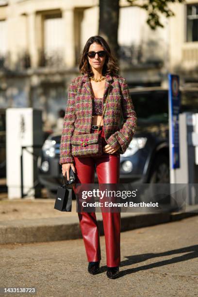 Guest wears black sunglasses, a gold large necklace, a blue / yellow / red tweed jacket from Chanel, a matching blue / yellow / red tweed crossbody...