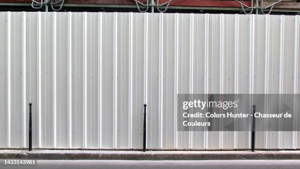 white metal palisade in front of a construction site and asphalt street in paris, france - way foundation stock pictures, royalty-free photos & images