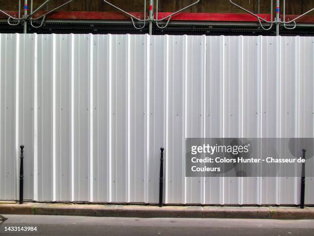 white metal palisade in front of construction site with scaffolding and asphalt street in paris, france - palisades pictures stock pictures, royalty-free photos & images