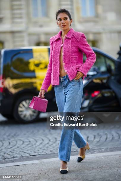 Guest wears crystal flower earrings, a pink fluffy jacket from Chanel, blue denim pants, a pink shiny leather ostrich shiny leather Kelly handbag...