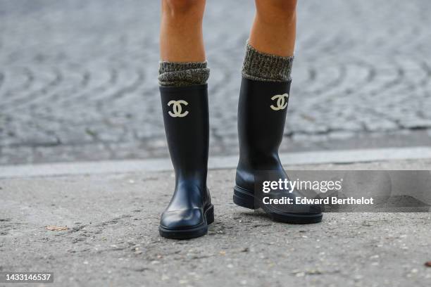 Guest wears gray wool high socks, black shiny plastic with embroidered white logo ankle boots from Chanel , outside Chanel, during Paris Fashion Week...