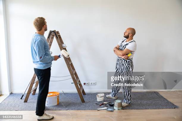 two men discussing while renovating their house - pensive bildbanksfoton och bilder