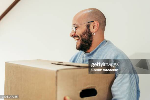 smiling young man with box moving to a new apartment - first apartment stock pictures, royalty-free photos & images