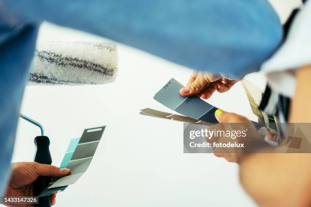 close-up of two men choosing the right color for their wall while renovating - painter in overhauls bildbanksfoton och bilder