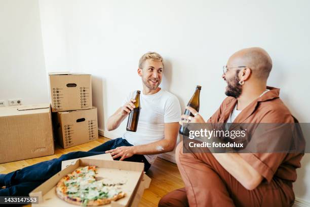 dois homens bebendo cervejas e comendo pizza durante a mudança da casa. - drinks carton - fotografias e filmes do acervo