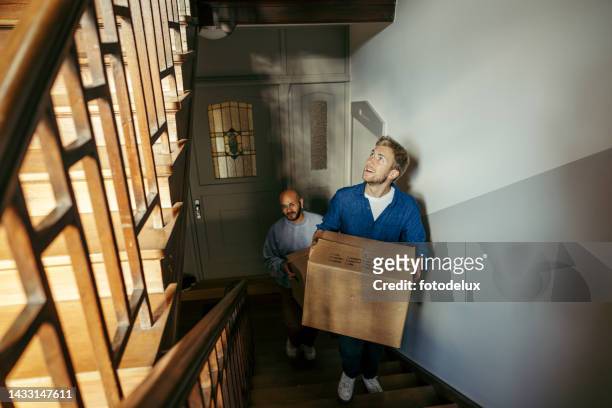 glückliche männliche freunde, die in eine neue wohnung ziehen - treppenhaus stock-fotos und bilder