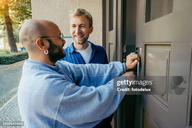 due uomini che aprono la nuova porta di casa con la chiave e sorridono - apartment front door foto e immagini stock