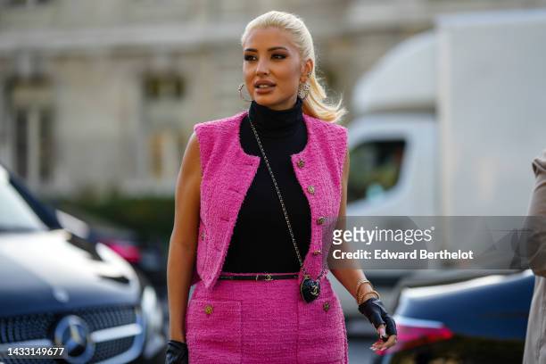 Guest wears silver and logo earrings from Chanel, a black turtleneck pullover, a pink tweed sleeveless jacket from Chanel, a pink tweed short skirt...
